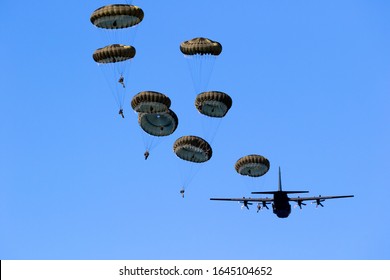 Military parachutist paratroopers jumping out of an air force airplane.