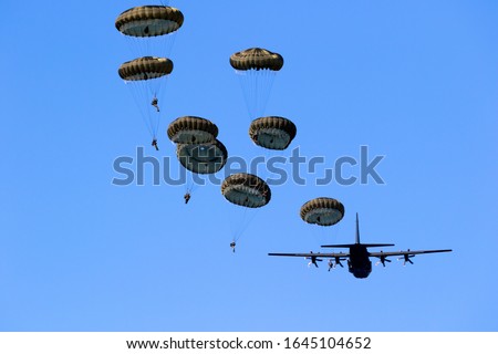 Military parachutist paratroopers jumping out of an air force airplane.