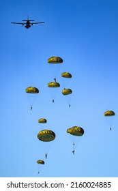 Military parachutist paratroopers parachute jumping out of a air force planes on a clear blue sky day. - Shutterstock ID 2160024885