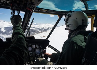 Military Pilot And Copilot Flying A UH-3H Sea King Helicopter Over Snowed Mountains. Andes, Bariloche.