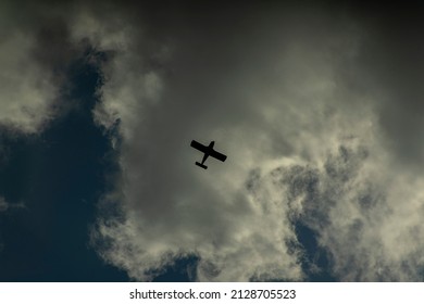 Military plane flying overhead in the sky. Camera angle looking up. Cloudy sky. Plane is a black silhouette shape. Concept for war. Plane in the centre, flying to the top right. 