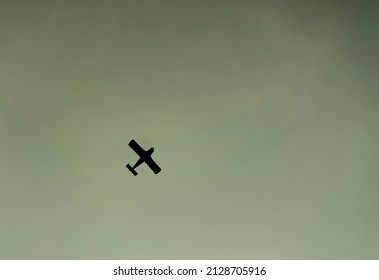 Military plane flying overhead in the sky. Camera angle looking up. Clear sky. Plane is a black silhouette shape. Concept for war. Plane in the centre, flying to the top right. Copy space to add text.