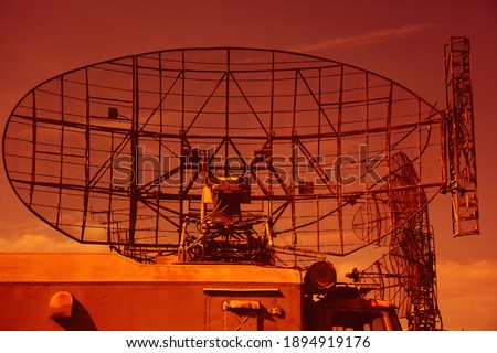 Military radar on the roof of a military vehicle. Military locator on a bright sky background