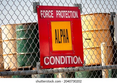 Military Sign On A Fence Stating Force Protection Alpha With Oil Drums In The Background 