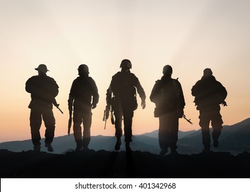 Military silhouettes of soldiers against the backdrop of sunset sky.