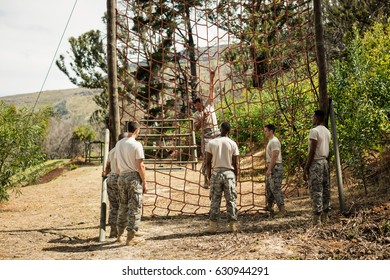 Military Soldier Climbing Rope During Obstacle Course In Boot Camp