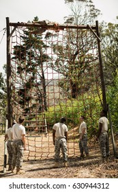 Military Soldier Climbing Rope During Obstacle Course In Boot Camp