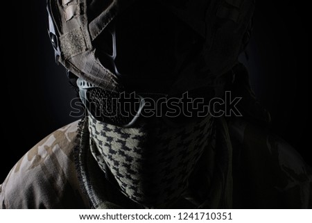 Military soldier head with camouflage  helmet, protective glasses and military scarf front closeup view on black background.