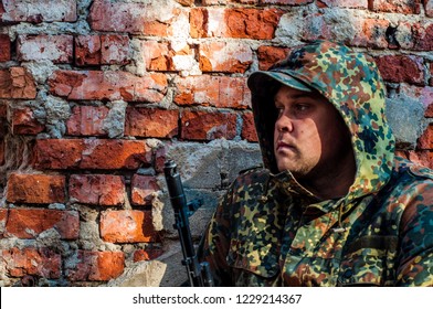 Military Soldier Hid Behind A Brick Wall,waiting Behind Cover.army Tactical Maneuvers. Training At The Military Training Ground.hooded Soldier Close-up. AKS -74. Kalashnikov Assault Rifle