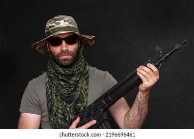 A Military Soldier With A Rifle In His Hands And Dark Glasses On A Black Background, Looks Into The Camera. Concept: Military Action, Soldier Of Fortune, Army Offensive.