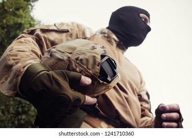 Military soldier in uniform and tactical gloves ready for a fight holding a camouflage helmet chest view. - Powered by Shutterstock