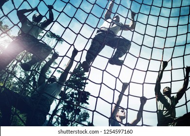 Military soldiers climbing rope during obstacle course in boot camp - Powered by Shutterstock