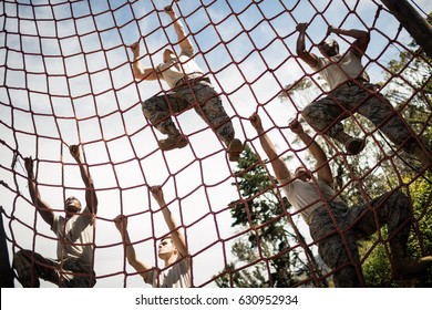 Military soldiers climbing rope during obstacle course in boot camp - Powered by Shutterstock