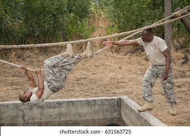 Military soldiers climbing rope during obstacle course training at boot camp - Powered by Shutterstock