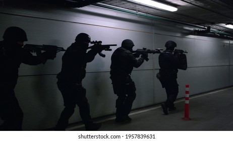 Military Soldiers In Helmets Storming Urban Building At Night. SWAT Police Officers Looking Through Scopes On Modern Rifles. Special Assault Team Aiming Targets On Firearms At Mission 