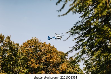 A Military Stealth Helicopter Flies Low Near Green Trees Against A Blue Sky. Photo Of The Vehicle.