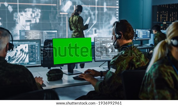 Military Surveillance Officer Working on\
Computer with Green Screen in Central Office for Cyber Operations,\
Control and Monitoring for Managing National Security, Technology\
and Army\
Communications.