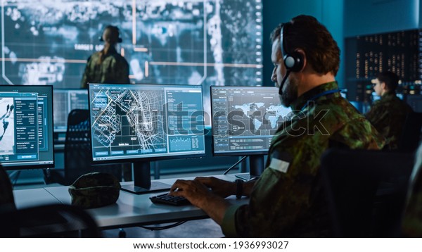 Military Surveillance Officer Working on\
a City Tracking Operation in a Central Office Hub for Cyber Control\
and Monitoring for Managing National Security, Technology and Army\
Communications.