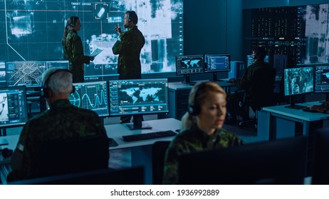 Military Surveillance Team Of Officers Locked A Target On A Vehicle From A Satellite And Monitor It On A Big Display In Office For Cyber Operations For Managing Security And Army Communications.