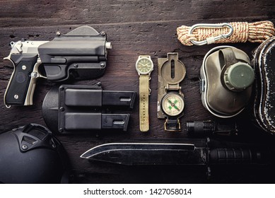 Military tactical equipment for the departure. Assortment of survival hiking gear on wooden background. Top view - vintage film grain filter effect styles