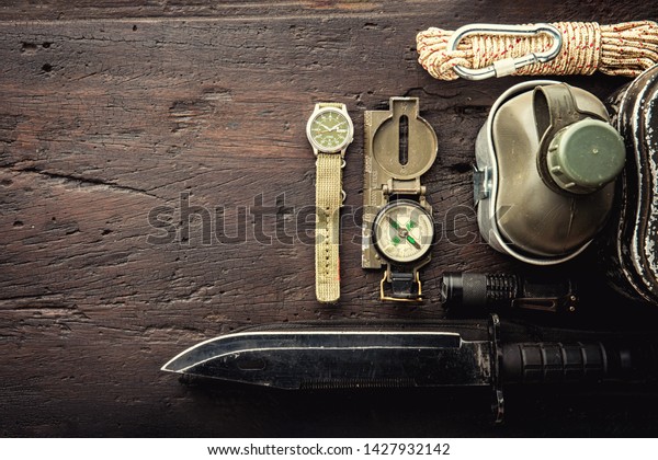 Military tactical equipment for the\
departure. Assortment of survival hiking gear on wooden background.\
Top view - vintage film grain filter effect\
styles