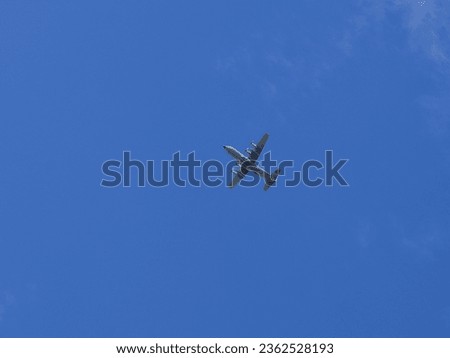Military transport aircraft flying overhead under the blue sky.