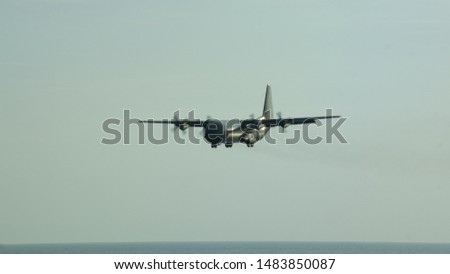 Military Transport C-130 Flying Over The Sea During Sunset.