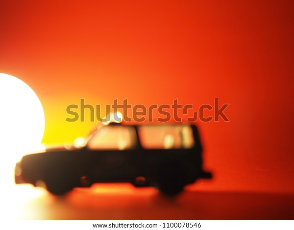 Military vehicles model parked\
on a red background and the light from fire, make it look like\
sunset.