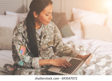 Military woman chatting on the laptop in bed