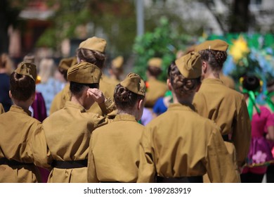 Military woman.A group of young slender girls in military uniform in a khaki tunic and with long dark hair gathered in a hairstyle in a garrison cap on their head.Photo female cadet back view