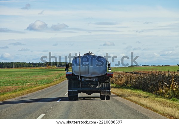 Milk barrel truck drive on countryside road .\
Liquid food goods delivery