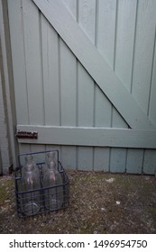 Milk bottle holder in front of a wooden gate