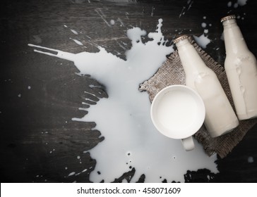 Milk Bottle And Milk Spilled On Dark Wood,top View