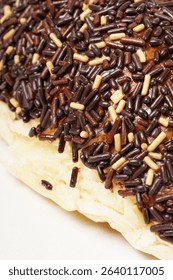 Milk bread with a soft white interior, topped generously with chocolate sprinkles and a touch of white topping. Photographed against a clean white background.