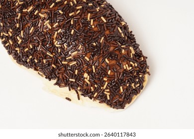 Milk bread with a soft white interior, topped generously with chocolate sprinkles and a touch of white topping. Photographed against a clean white background.