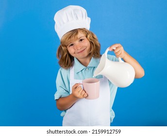 Milk For Children. Child Chef Cook Prepares Food In Isolated Blue Studio Background. Kids Cooking. Teen Boy With Apron And Chef Hat Preparing A Healthy Vegetables Meal In The Kitchen.