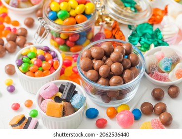 Milk chocolate candies in shell with jelly sugar gums and liquorice allsorts and fruit sherbet candies on white background. with marshmallows and strawberry bon bons.