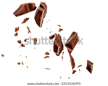  Levitating milk chocolate chunks isolated on white background. Flying Chocolate pieces, shavings and cocoa crumbs Top view. Flat lay