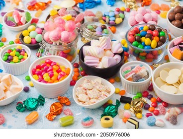 Milk chocolate and jelly gums candies on blue with liquorice allsorts and strawberry bonbons and large variety of sweets and candies. Top view - Shutterstock ID 2050976006
