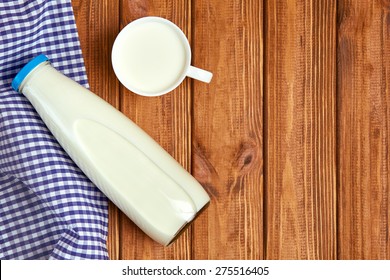 Milk Cup And Bottle On Wooden Table. Top View With Copy Space