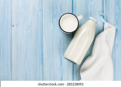 Milk Cup And Bottle On Wooden Table. Top View With Copy Space