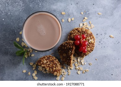 Milk Drink With The Taste Of Chocolate In A Clear Glass With Cookies, Cereals, Currants And Mint On A Gray Background.  Background Image, Copy Space, Horizontal