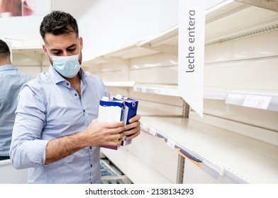 Milk Empty Shelf In The Supermarket In Spain. Leche Entera Means Whole Milk. A Man Panic Buying In The Store Due To Food Shortage In 2022 In Europe. He Wears A Face Mask And Holds Two Milk Tetra Pack