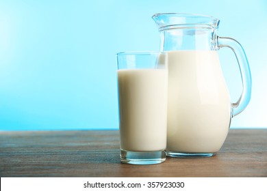 Milk in glass and in jar on table on blue background - Shutterstock ID 357923030
