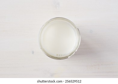 Milk In A Glass On A White Table Top View