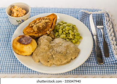 Milk Gravy On Pork Cube Steak Served With Baked Sweet Potato, Lima Beans And Carrot And Raisin Salad.  Blue Gingham Place Mat To Emphasize Country Style Cooking.