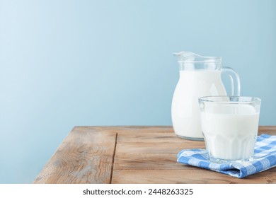 Milk in jug and glass on wooden table and blue background. Concept of farm dairy products, milk day. Kitchen or supermarket mock up for design. Copy space. - Powered by Shutterstock