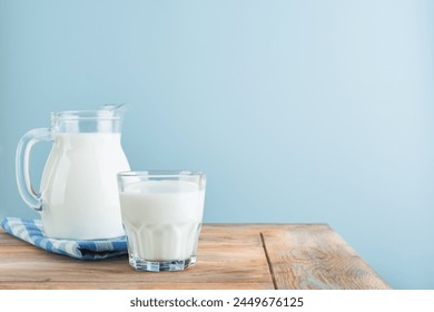 Milk in jug and glass on wooden table and blue background. Concept of farm dairy products, milk day. Kitchen or supermarket mock up for design. Copy space. - Powered by Shutterstock