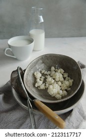 Milk Kefir Grains In A Gray Plate With A Bottle And A Cup Of Kefir On White Table.