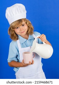 Milk For Kids. Child Chef Cook Prepares Food In Isolated Blue Studio Background. Kids Cooking. Teen Boy With Apron And Chef Hat Preparing A Healthy Vegetables Meal In The Kitchen.